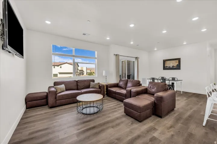 Spacious living area featuring wood-finish flooring, recessed lighting, and white walls