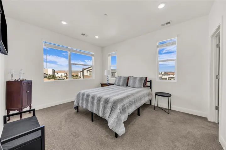 Bedroom featuring light gray carpeting, multiple windows with blinds, recessed lighting, and a white six-panel door