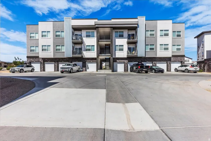 Contemporary multi-story building featuring a facade of grey and white siding, stone veneer accents, and multiple private balconies
