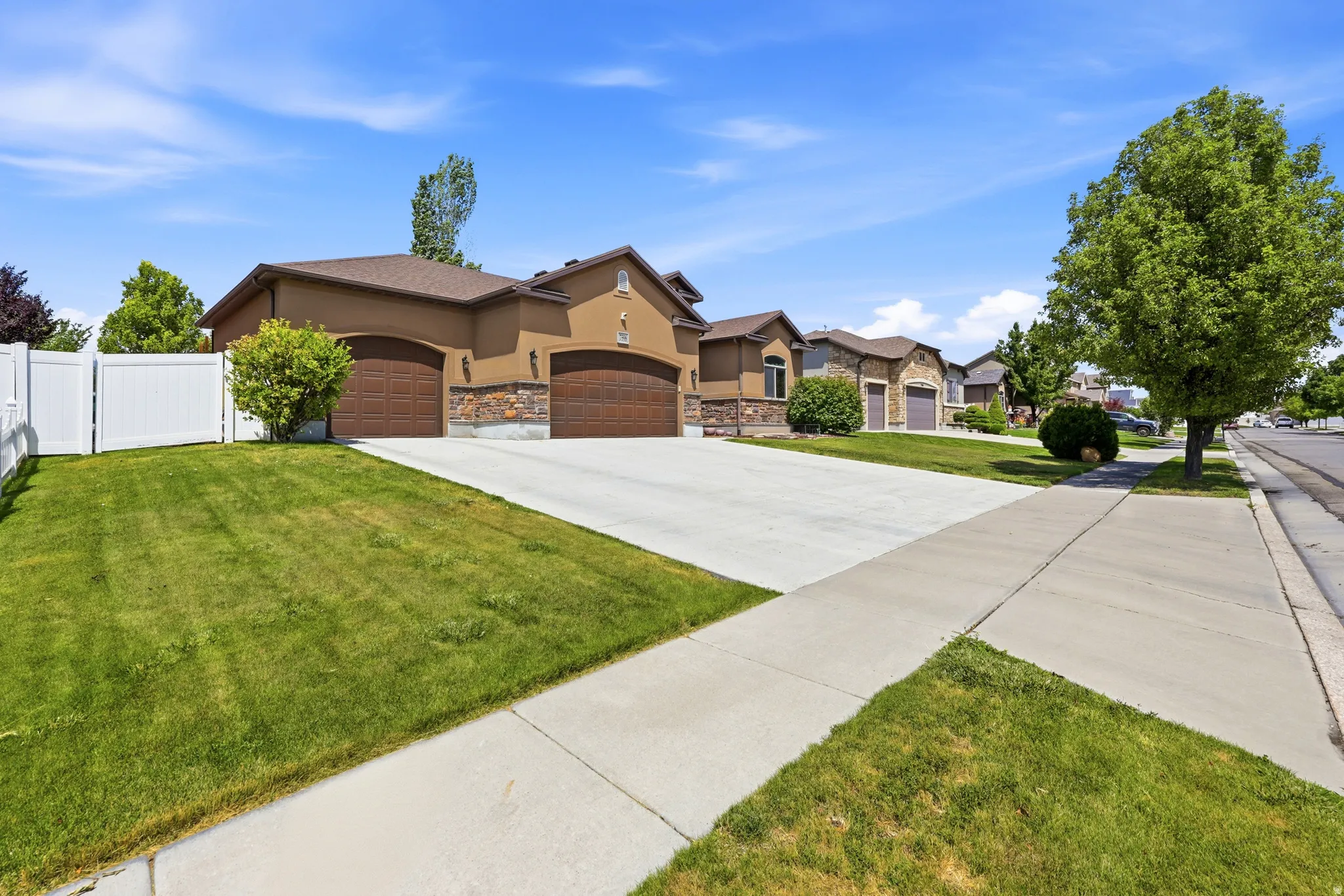 Two-car garage with arched doors, stone facade accents, and a stucco exterior