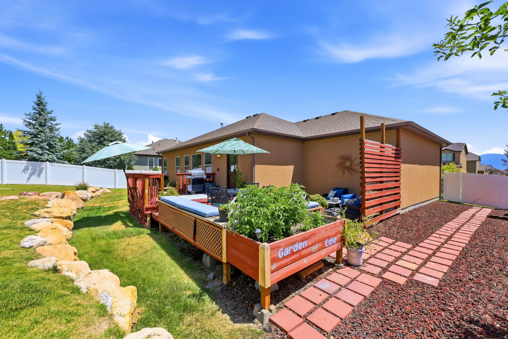 Spacious backyard featuring a multi-level deck, built-in planter boxes, a terraced lawn area, a white vinyl privacy fence, and a decorative slatted wood screen