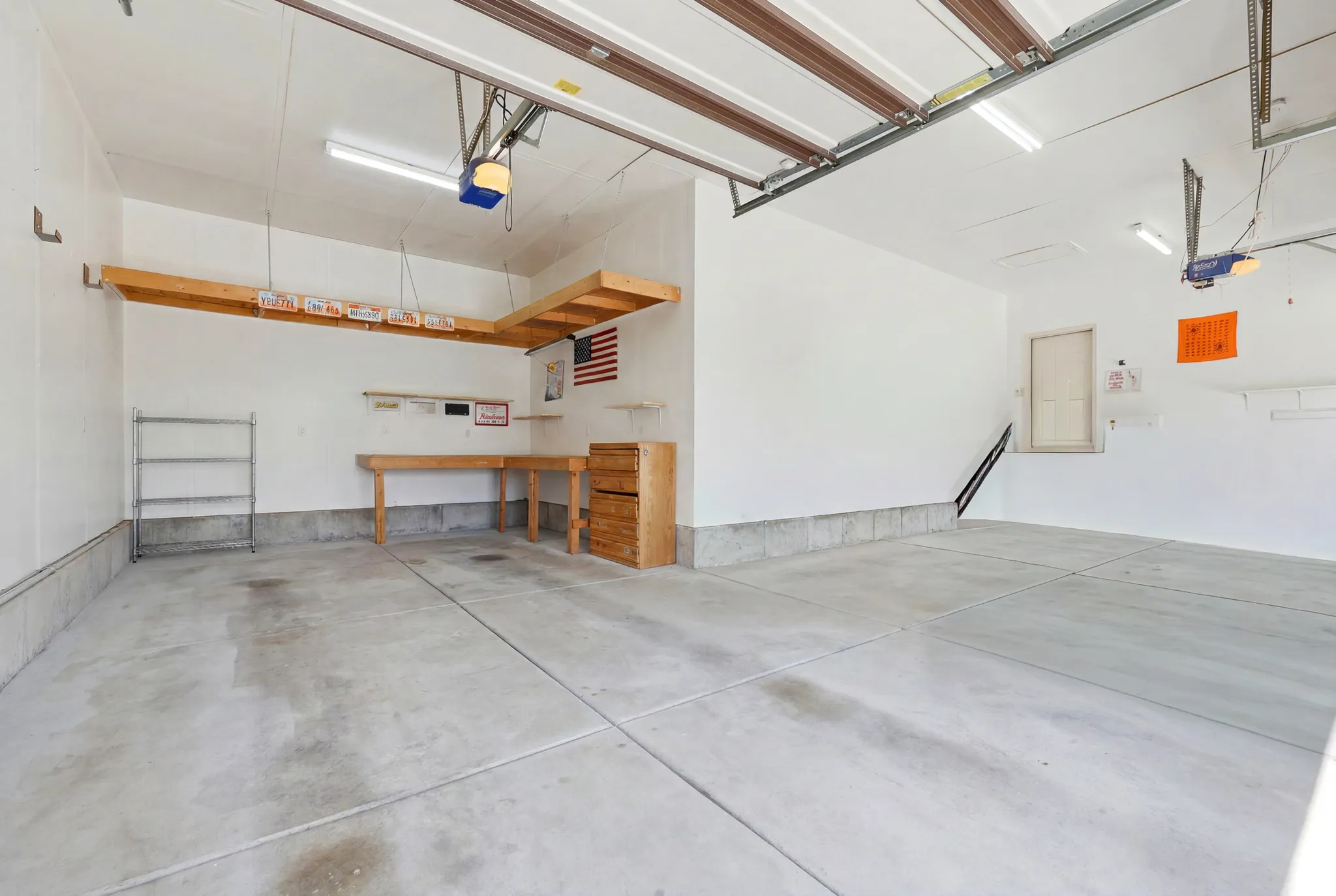 Spacious garage featuring a concrete floor, overhead lighting, and two garage door openers