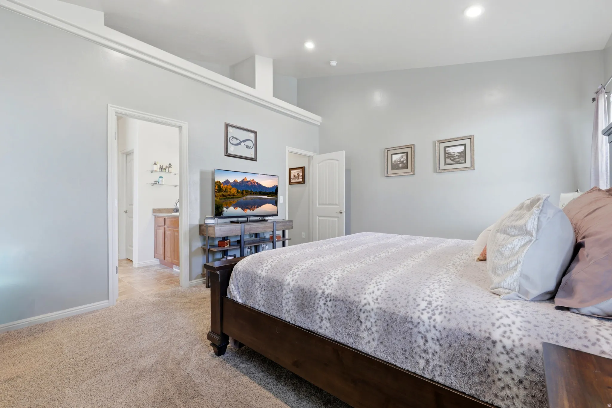 Carpeted bedroom with light gray walls, recessed lighting, and a vaulted ceiling feature