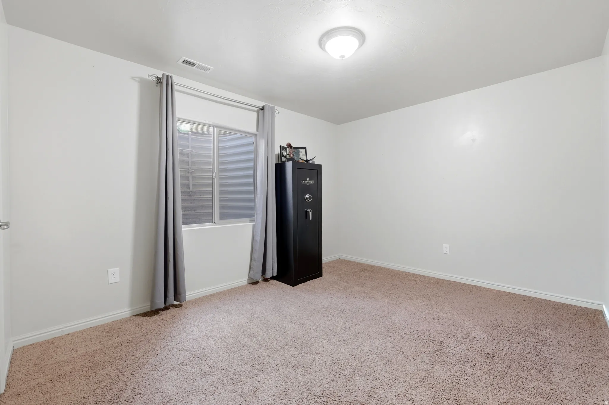 Spacious room featuring neutral carpeting, white baseboards, and a window with horizontal blinds
