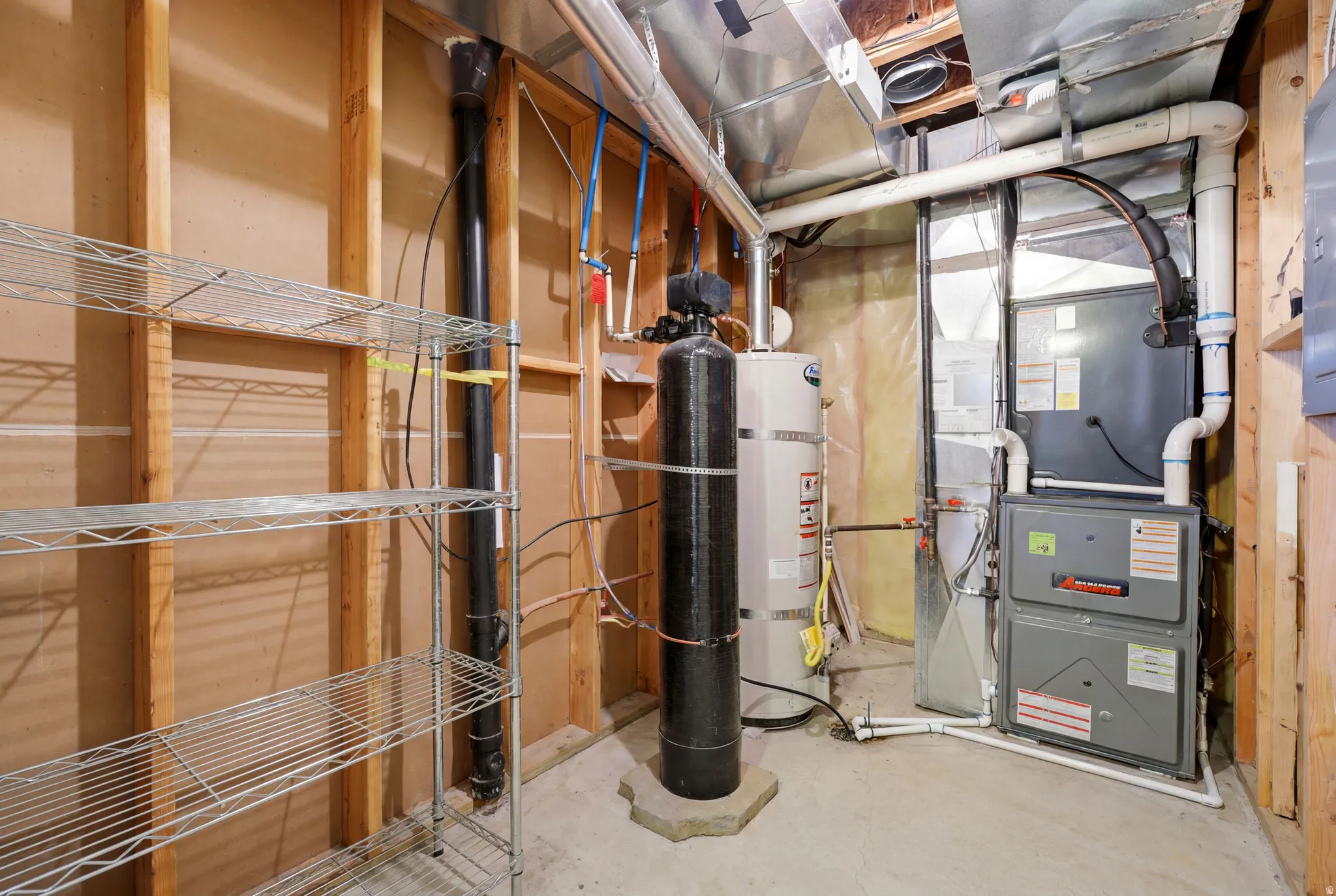 Utility room featuring a furnace, water heater, water treatment system, and exposed wood framing