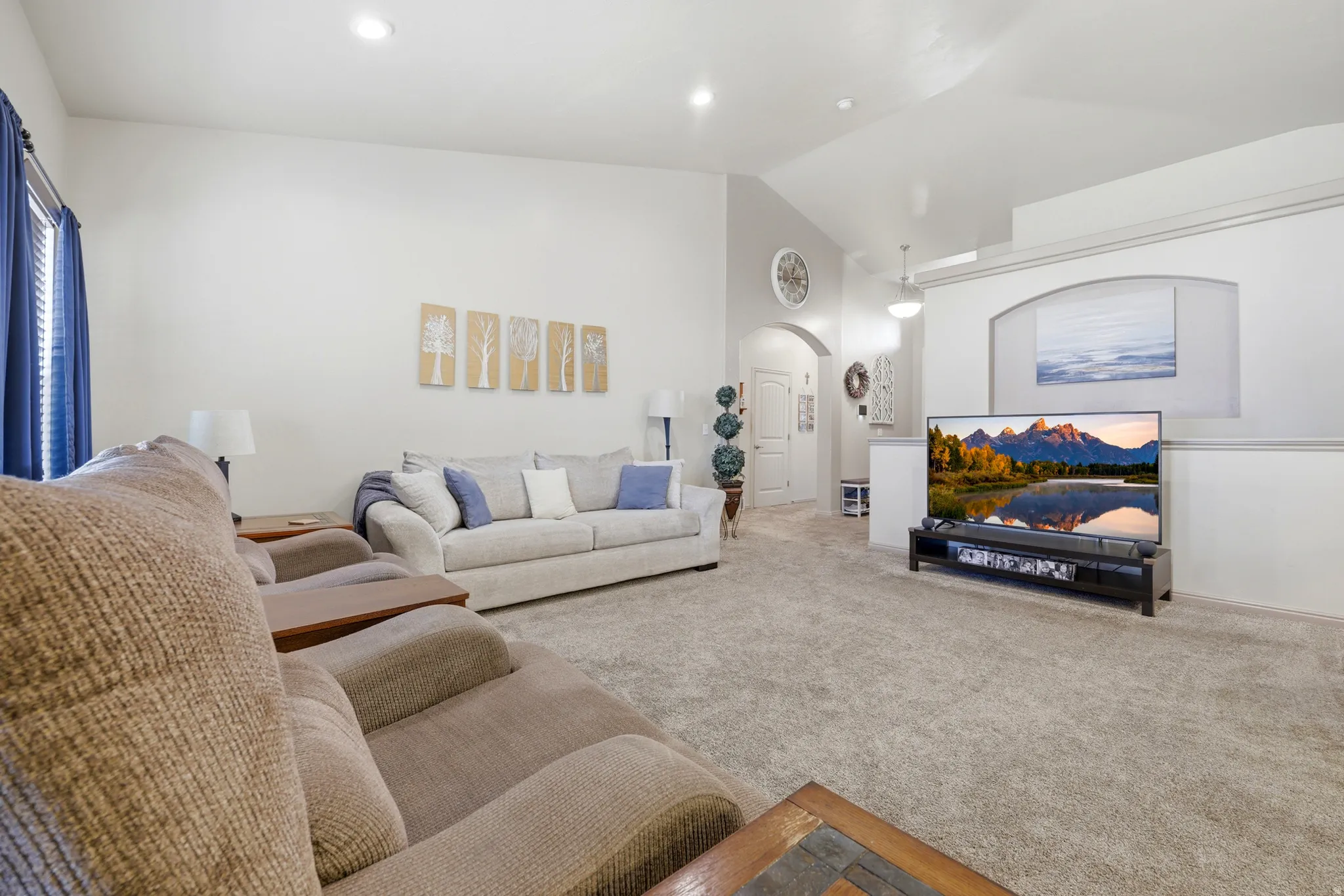 Spacious living area featuring vaulted ceilings, recessed lighting, and soft gray carpeting