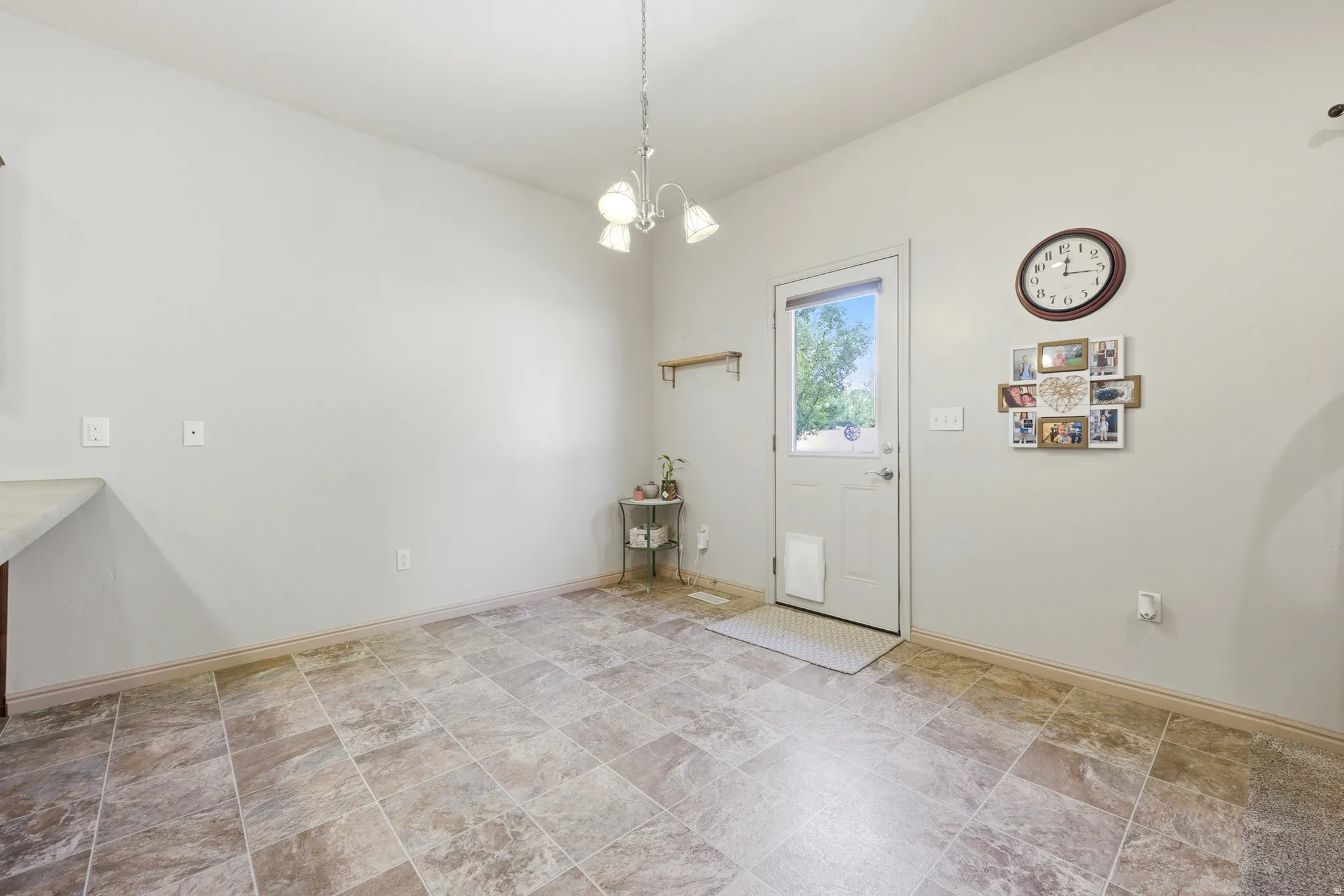 Neutral tone interior space featuring a glass-paneled exterior door, patterned tile flooring, and a ceiling-mounted light fixture