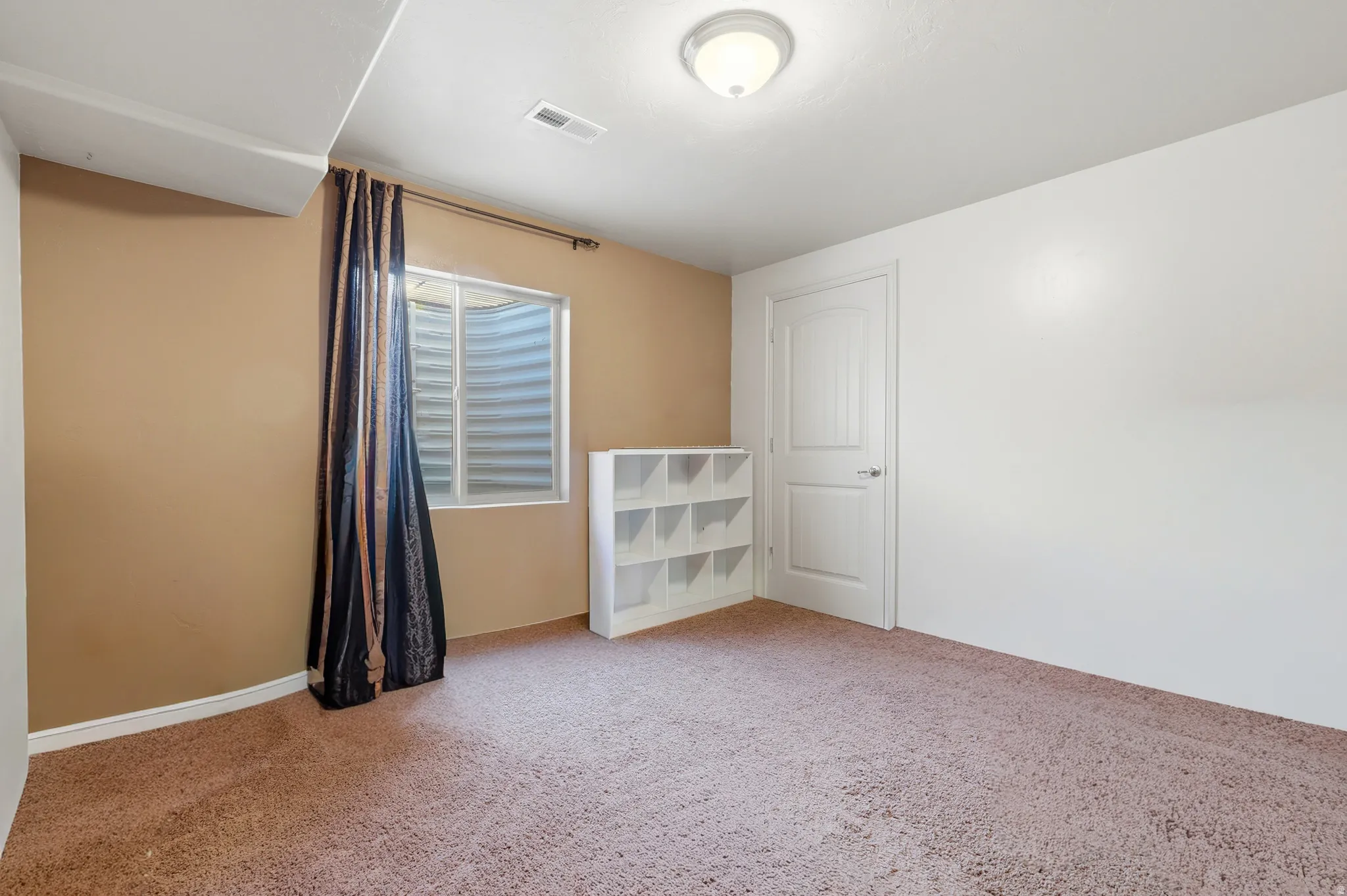 Carpeted room with a flush-mount ceiling light, white trim, and a white paneled door