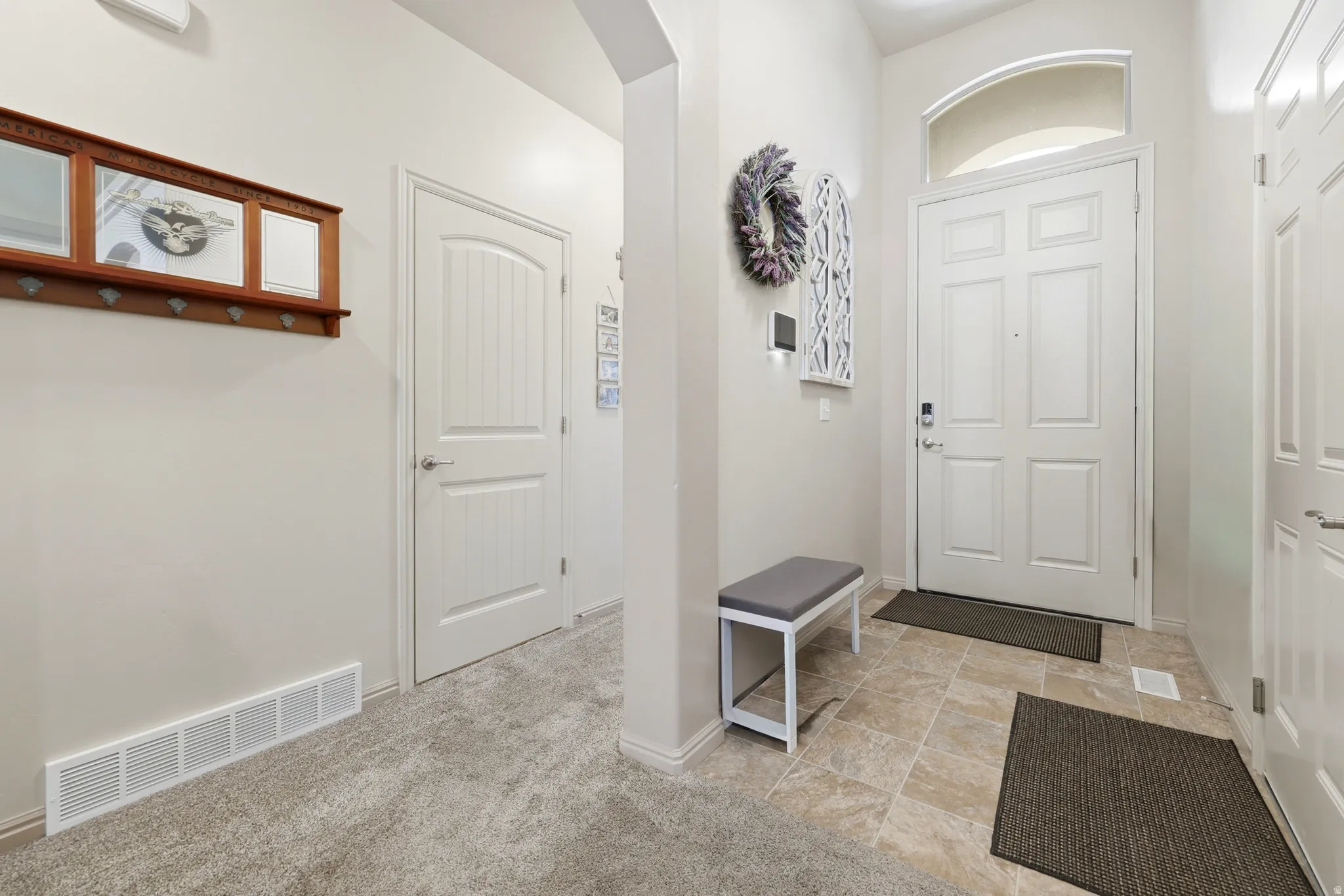 Entryway featuring a paneled door with an arched transom window, ceramic tile flooring, and light-colored walls