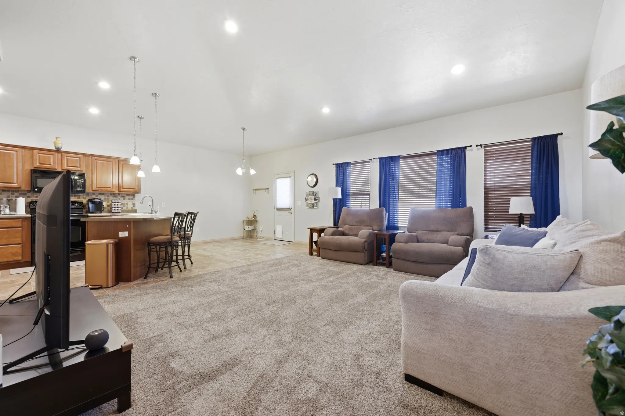 Open-concept living area featuring a kitchen with wood cabinetry, a breakfast bar, and pendant lighting