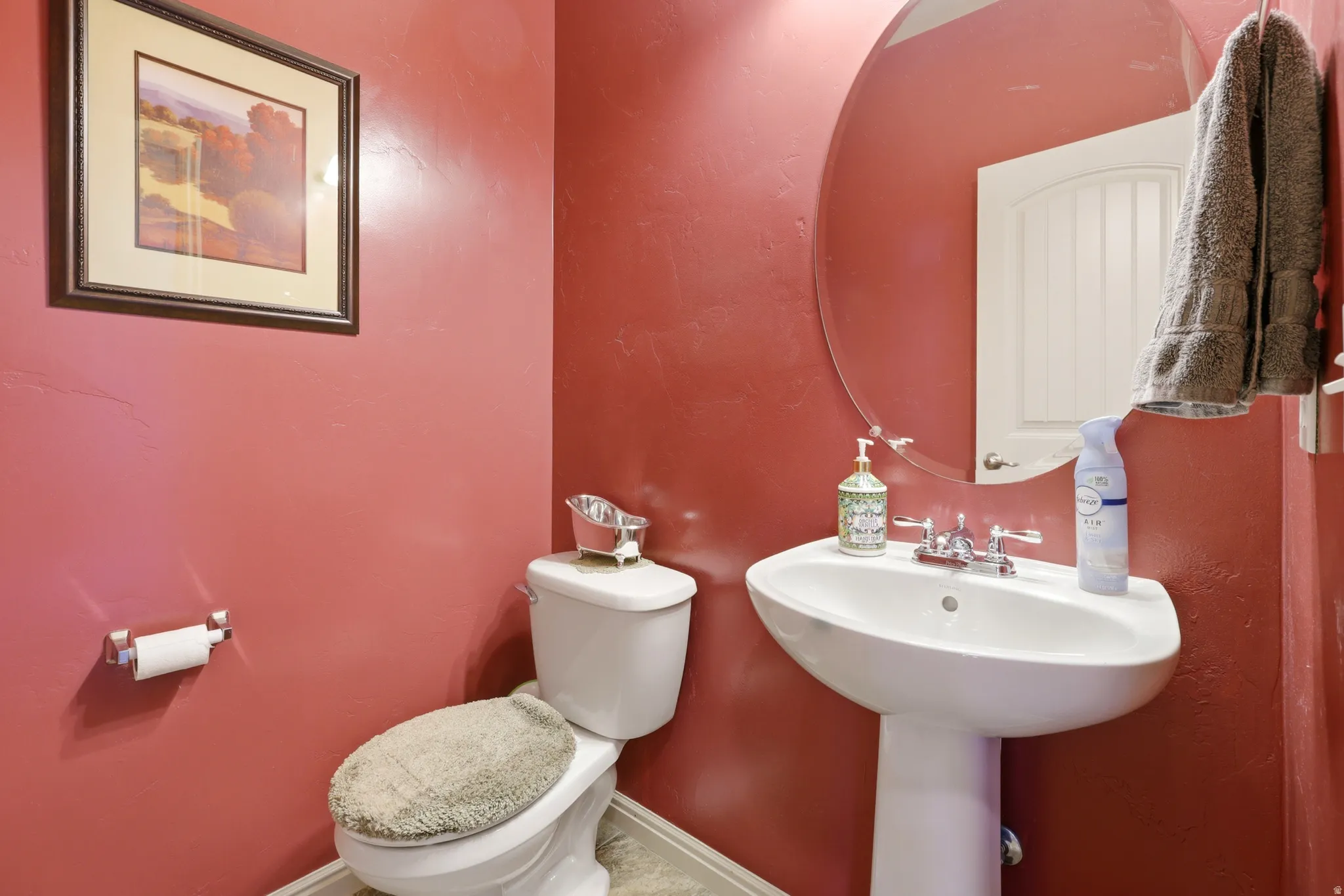 Bathroom featuring a pedestal sink, oval mirror, and a white toilet