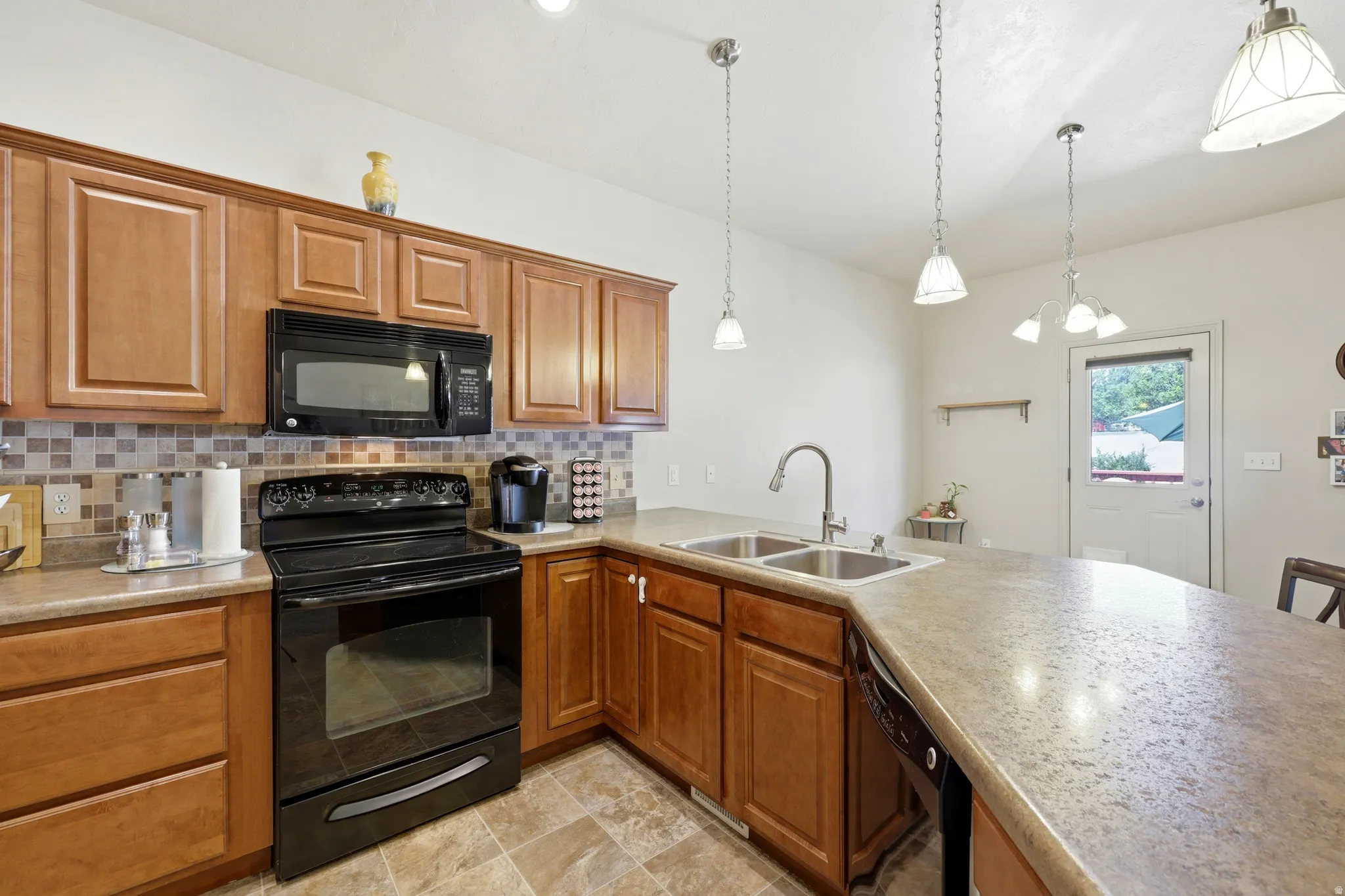 Kitchen featuring light wood cabinetry, a tiled backsplash, and dark countertops