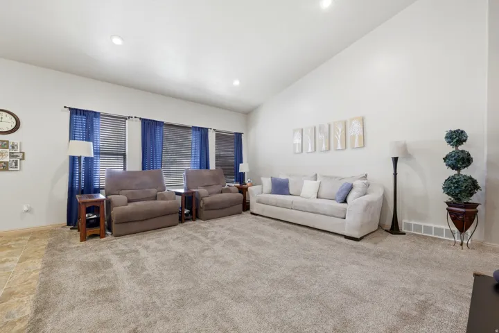 Spacious room featuring vaulted ceilings, recessed lighting, and large windows with blinds