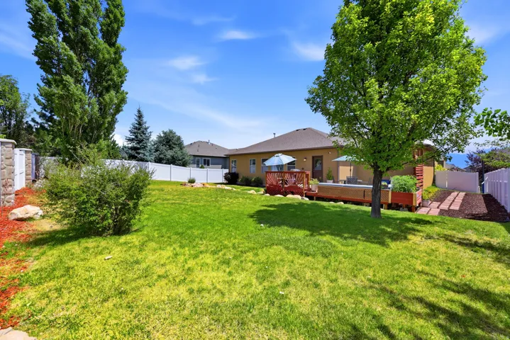 Expansive backyard featuring a manicured lawn, a multi-level wood deck, and mature trees