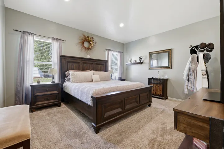 Spacious room featuring neutral carpeting, recessed lighting, and two windows providing natural illumination