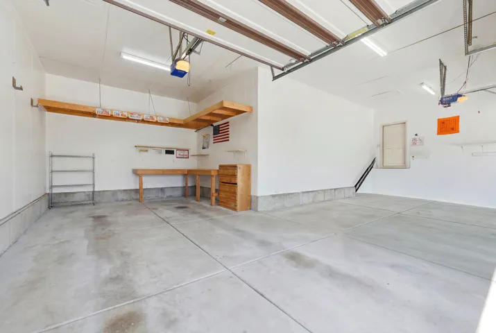 Spacious garage featuring a concrete floor, overhead lighting, and two garage door openers