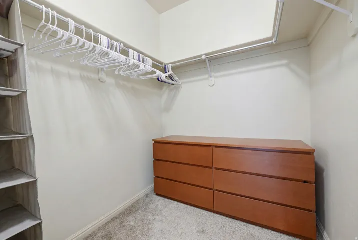Carpeted closet space featuring a built-in wood-finish six-drawer dresser