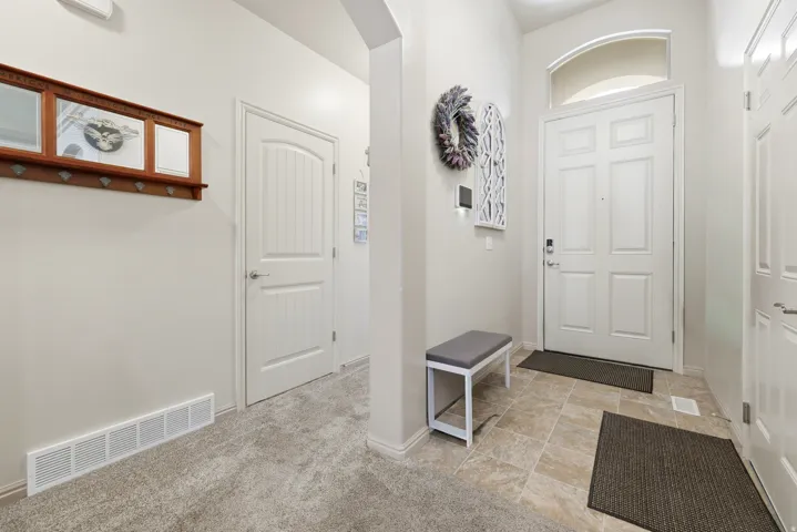 Entryway featuring a paneled door with an arched transom window, ceramic tile flooring, and light-colored walls