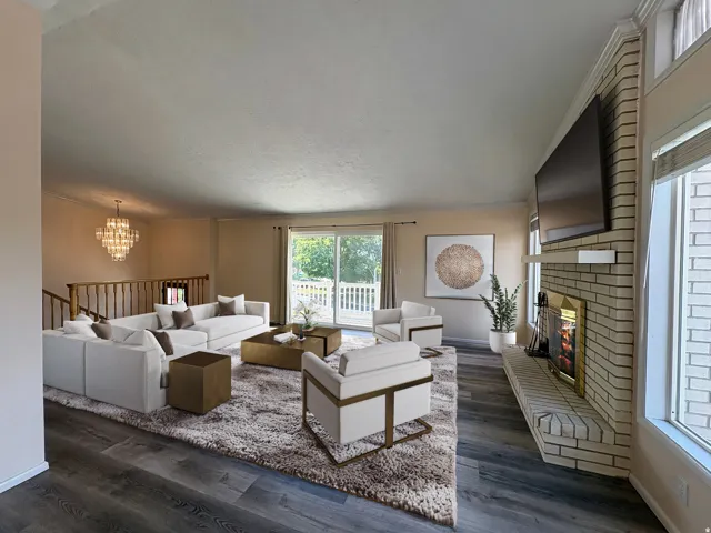 Spacious living area featuring wood-finish flooring, a white brick fireplace with mantel, and sliding glass doors opening to a private deck