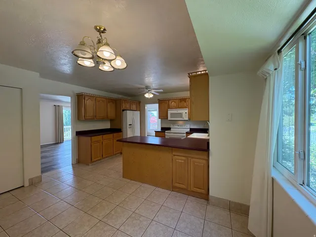 Kitchen featuring tile flooring, wood cabinetry, built-in microwave, and an island with countertop seating