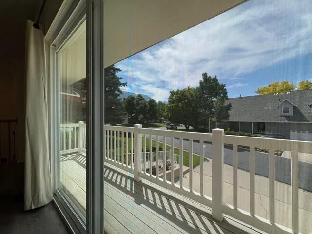 Outdoor balcony featuring wood-finish decking and white railings