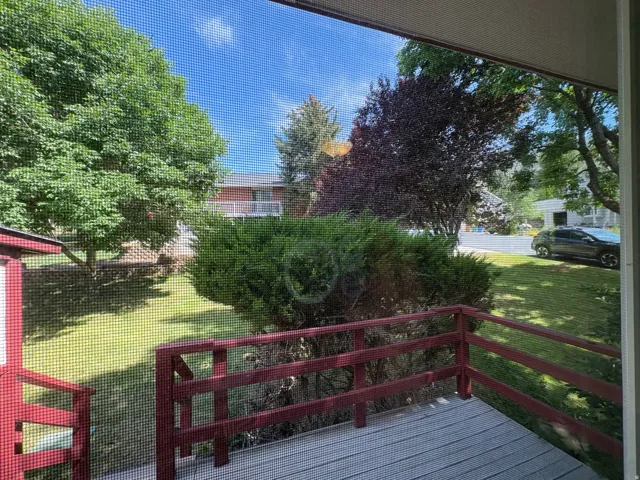 Private outdoor decking with red-painted railings overlooking a green lawn and mature landscaping