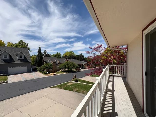 Exterior balcony featuring composite decking, white railing, and an adjacent sliding glass door