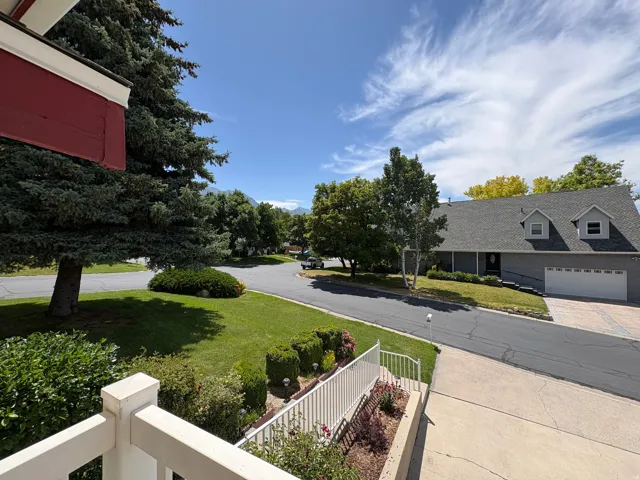 Suburban landscape featuring a well-maintained lawn, mature trees, and a paved driveway leading to a two-car garage