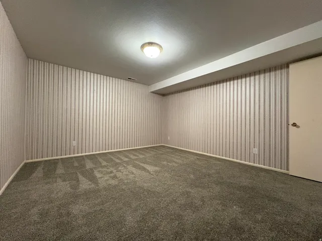 Room featuring striped wallpaper, neutral plush carpeting, and a flush-mount ceiling light