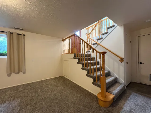 Carpeted staircase with natural wood banister and balusters