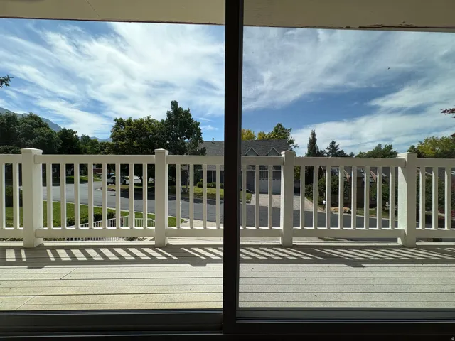 Outdoor deck featuring composite decking, white railing, and sliding glass door access