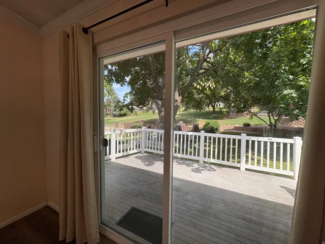 Sliding glass door opening to a wood-finish deck with white railings