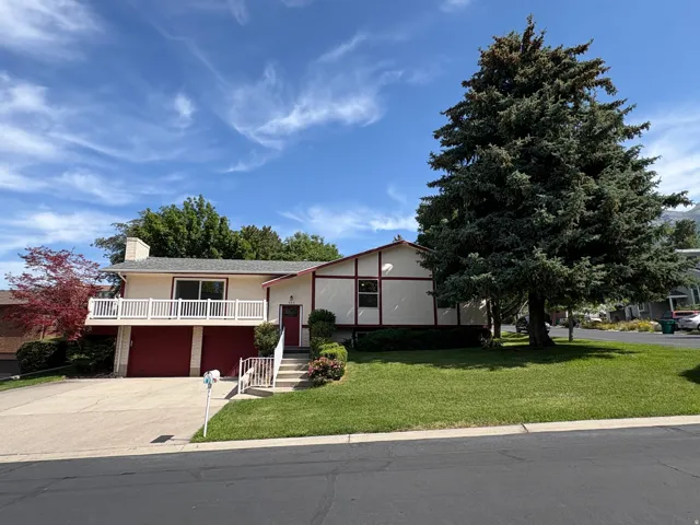 Split-level residence featuring a prominent balcony, dual garage doors, and a front yard with established landscaping