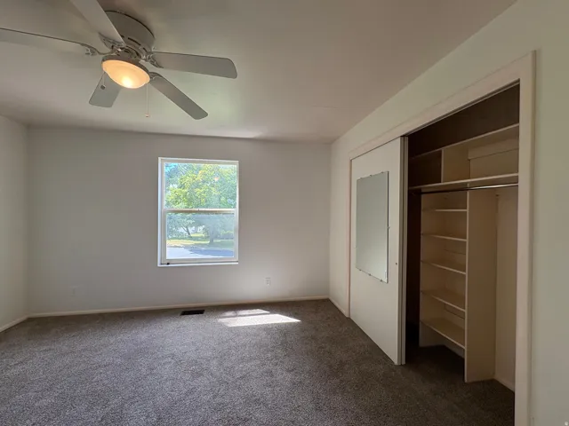 Room featuring a window, ceiling fan with integrated lighting, and carpeted flooring