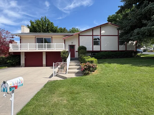 Split-level residence featuring a two-car garage with red doors and a front-facing balcony with white railing