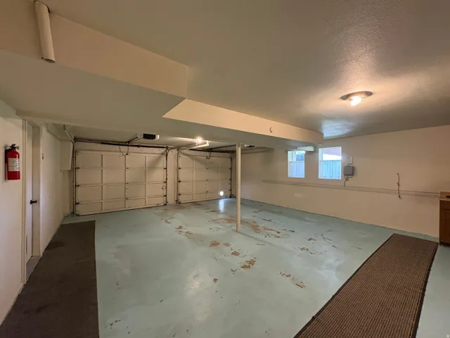 Spacious two-car garage with overhead doors, painted concrete flooring, and multiple windows providing natural light