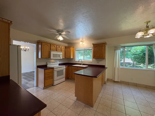 Kitchen featuring wood cabinetry, white appliances, and a ceiling fan