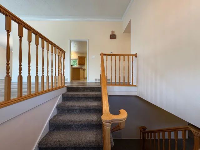 Carpeted staircase with light wood banister and balusters