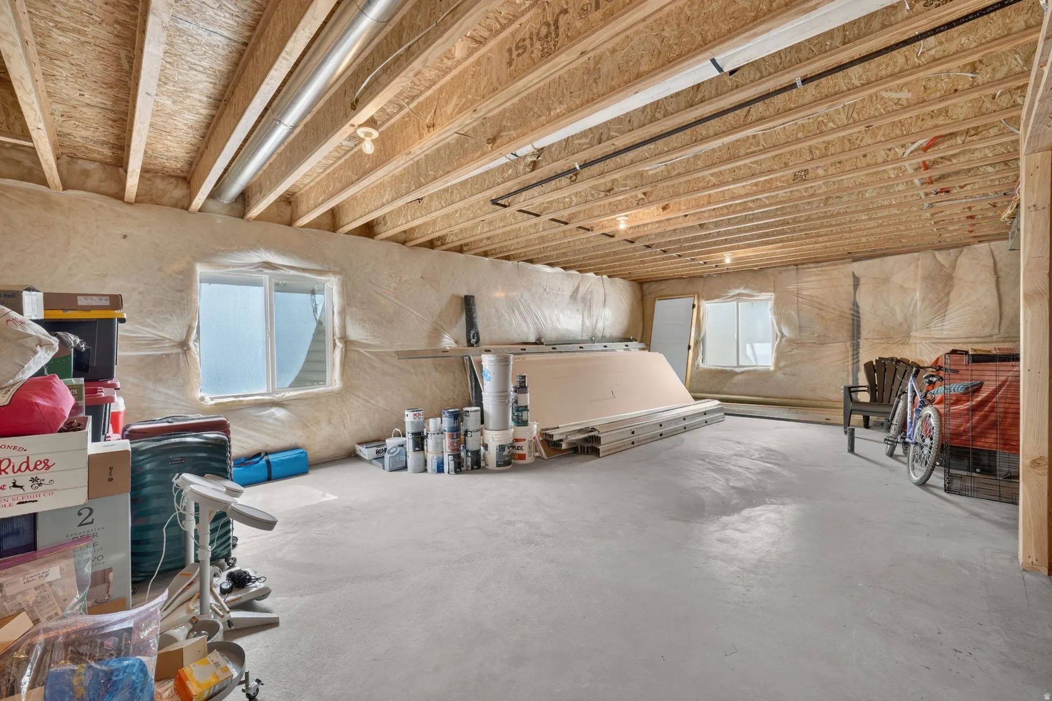 Unfinished lower level with exposed ceiling joists and concrete flooring