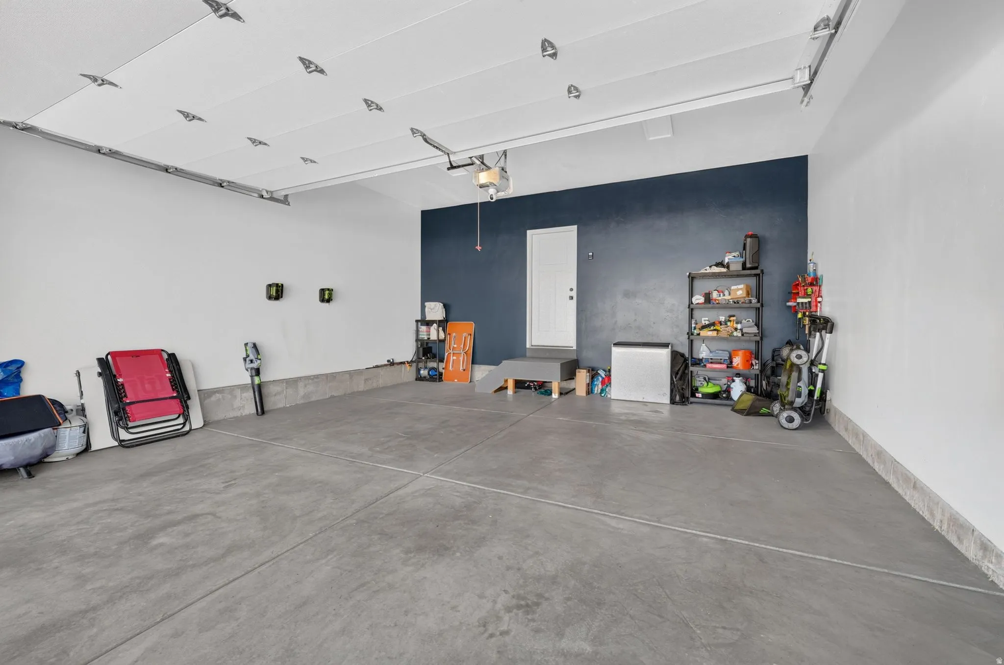 Spacious garage with concrete flooring, white walls, and a feature wall in a deep blue hue