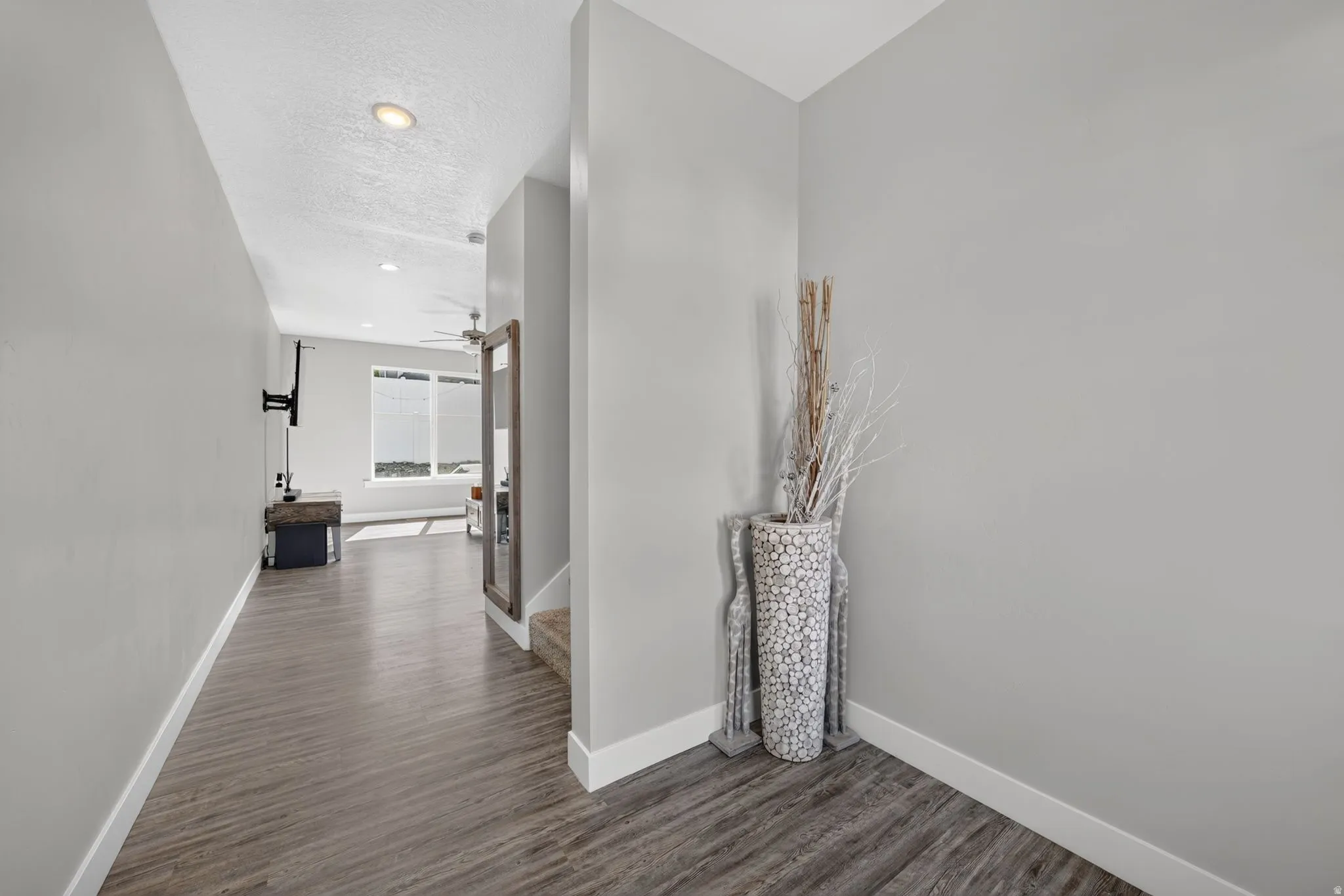 Hallway featuring wood-finish flooring, recessed lighting, and crisp white baseboards
