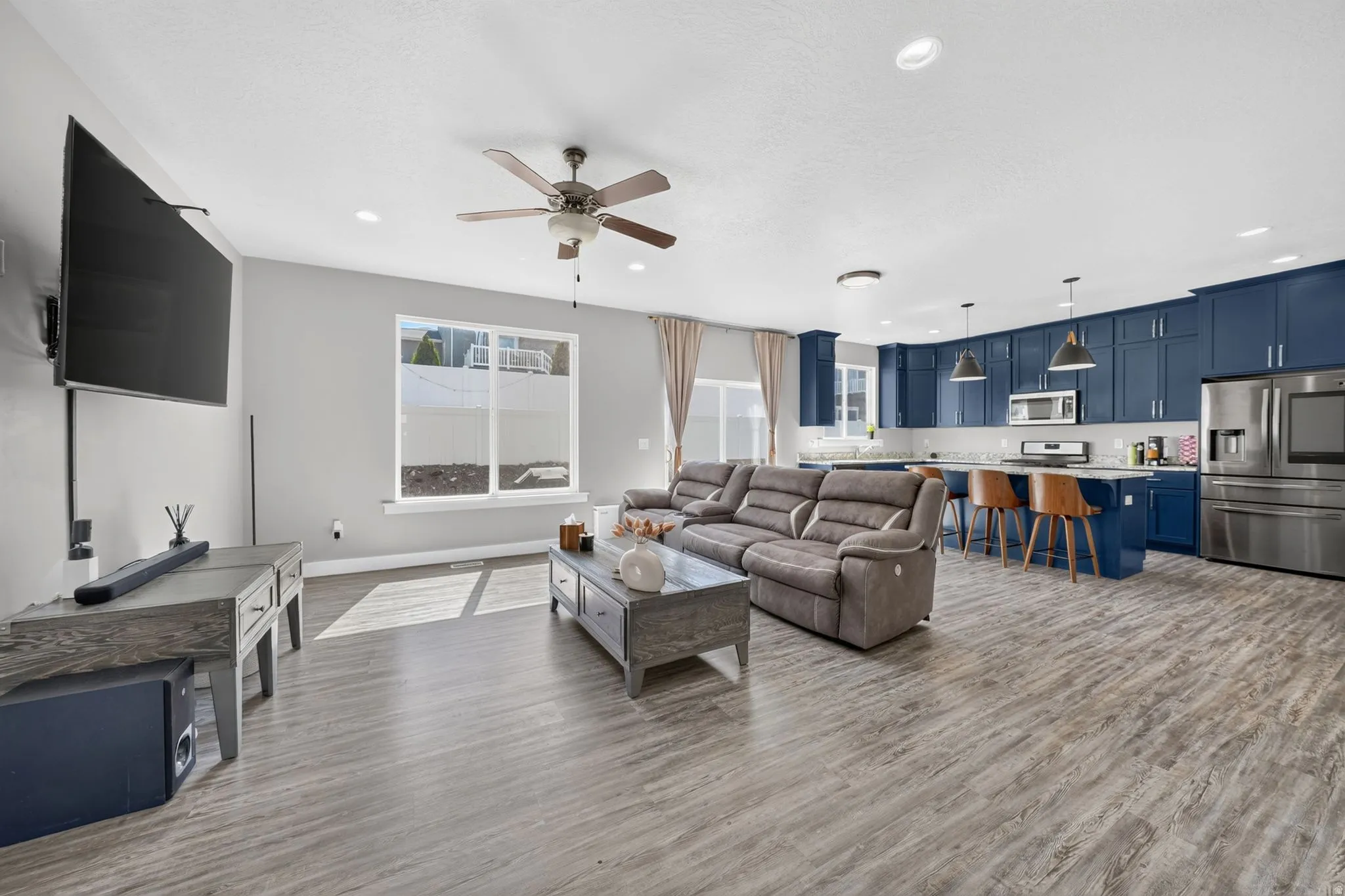 Open-concept living area featuring wood-finish flooring, a contemporary ceiling fan, and recessed lighting