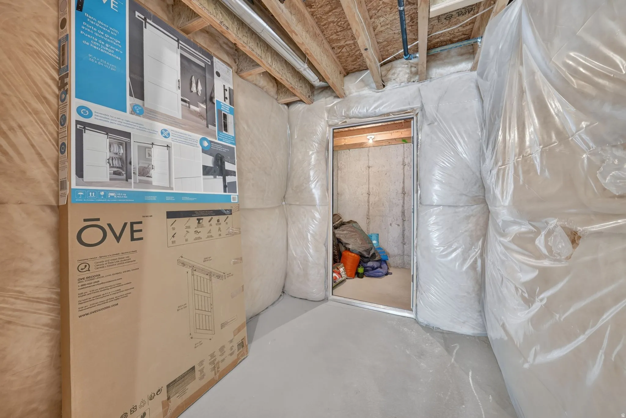 Unfinished basement space featuring exposed wood joists, insulated walls, and a concrete floor