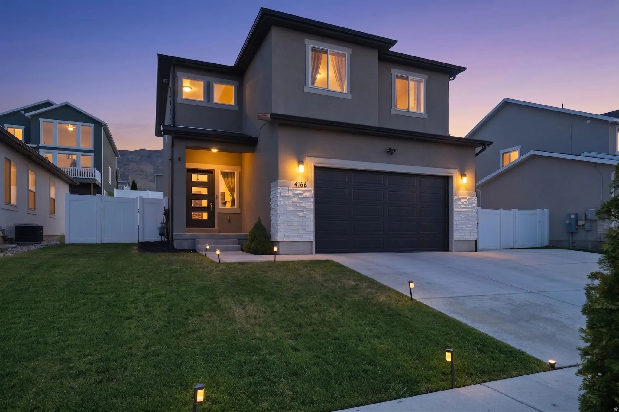 Contemporary two-story residence with a gray stucco exterior and white stacked stone accents