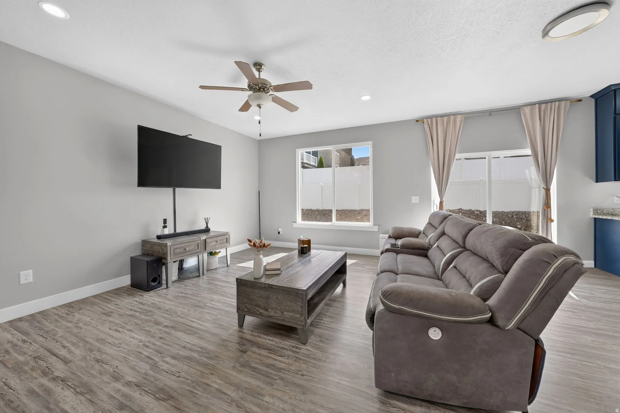 Open-concept living space with wood-finish flooring, recessed lighting, and a ceiling fan