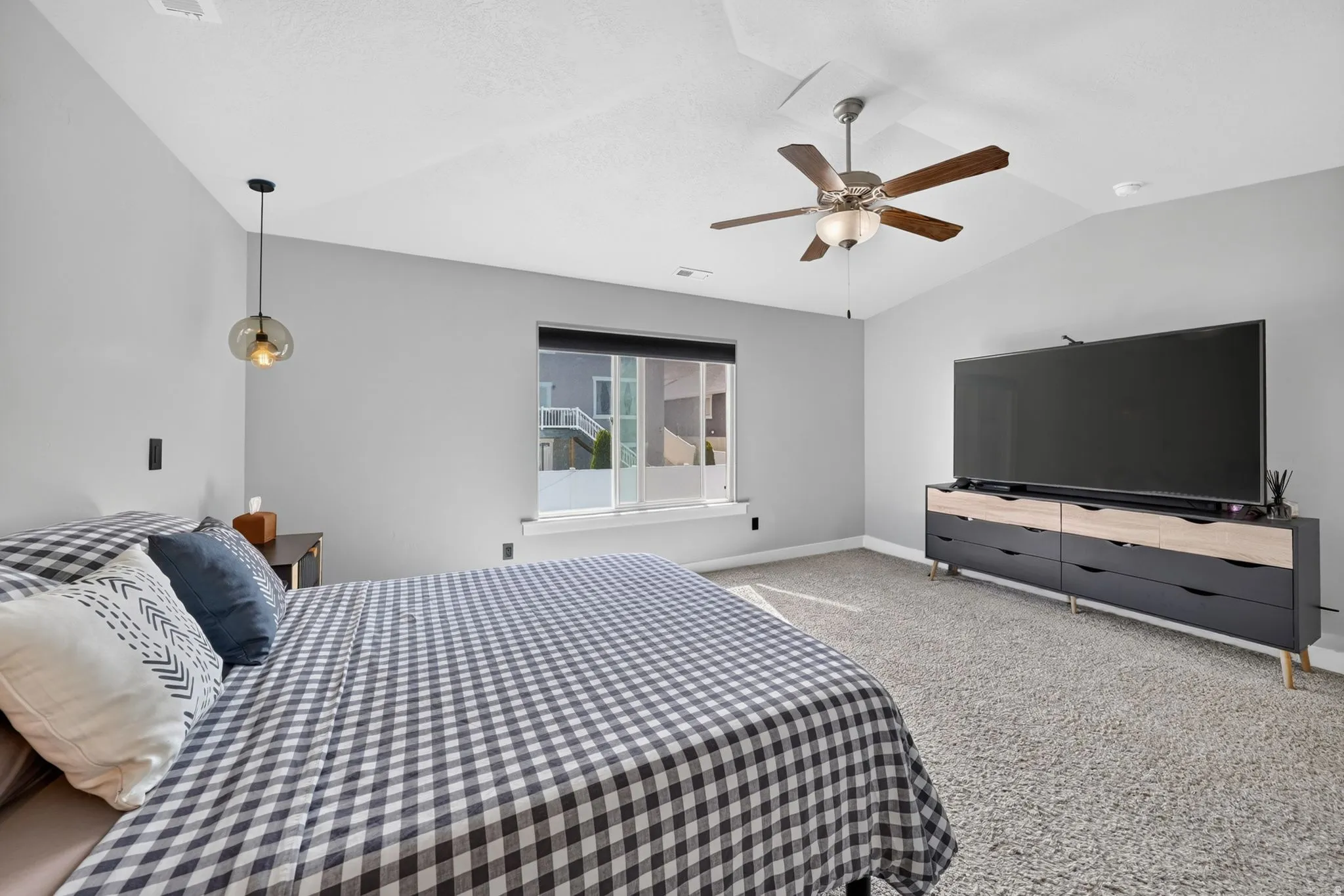 Spacious room featuring vaulted ceilings, a ceiling fan with integrated lighting, recessed lighting, a window with exterior visibility, and gray wall paint