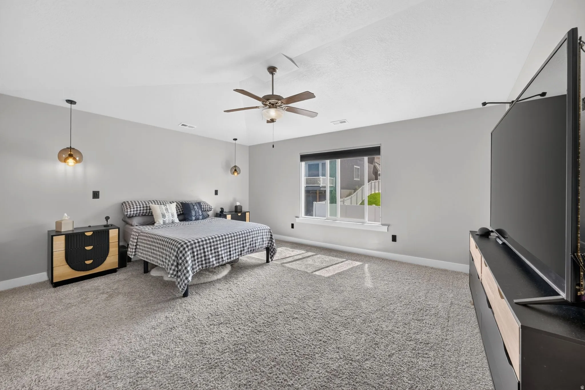Bedroom featuring light gray walls, plush gray carpeting, a ceiling fan, and two pendant light fixtures