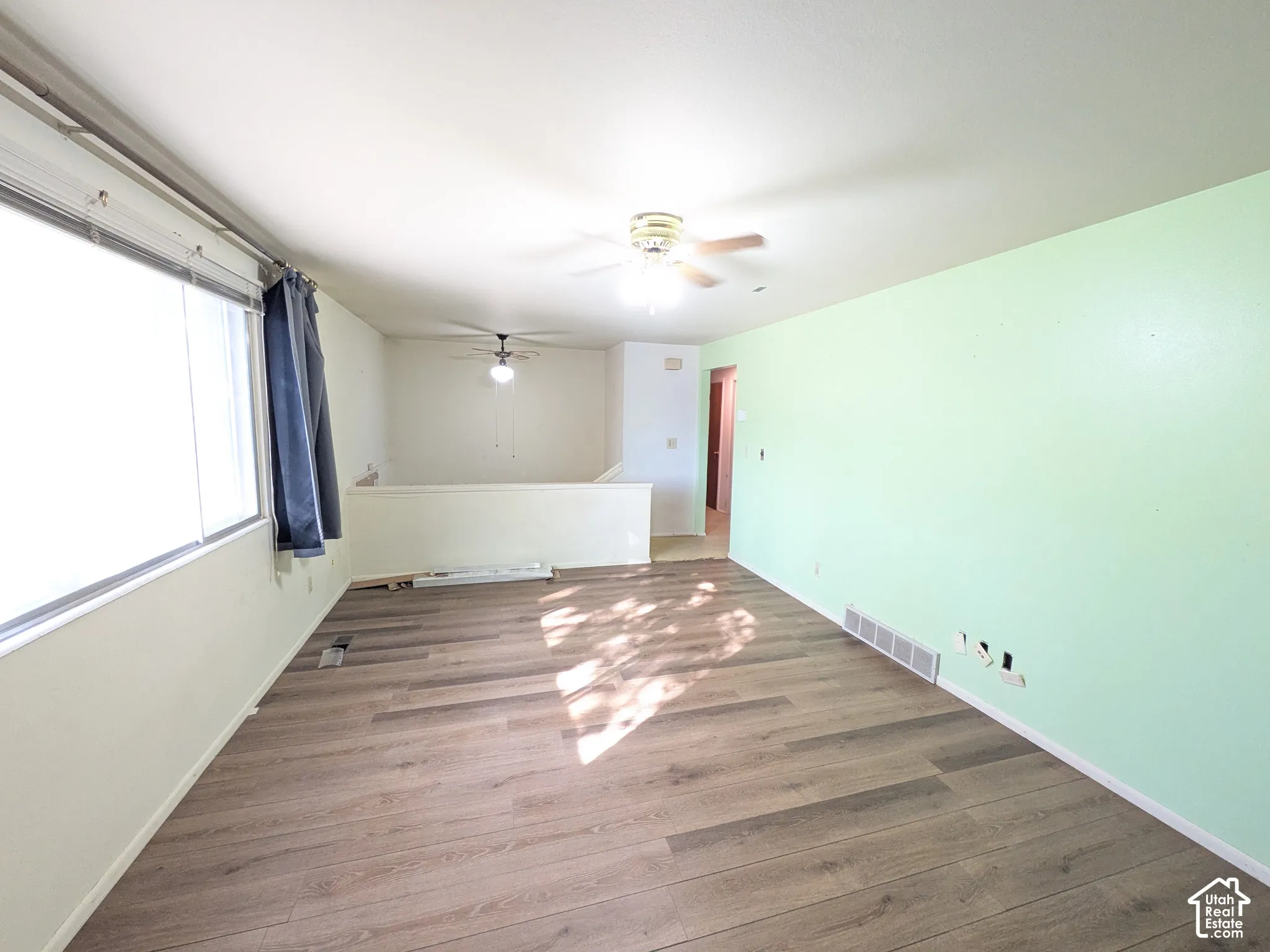 Wood-finish flooring, overhead ceiling fans, and a partial wall with open space