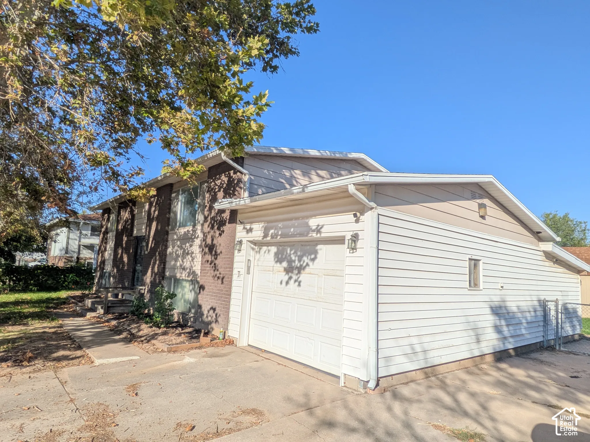 Attached two-car garage, brick facade with siding accents, and a paved driveway