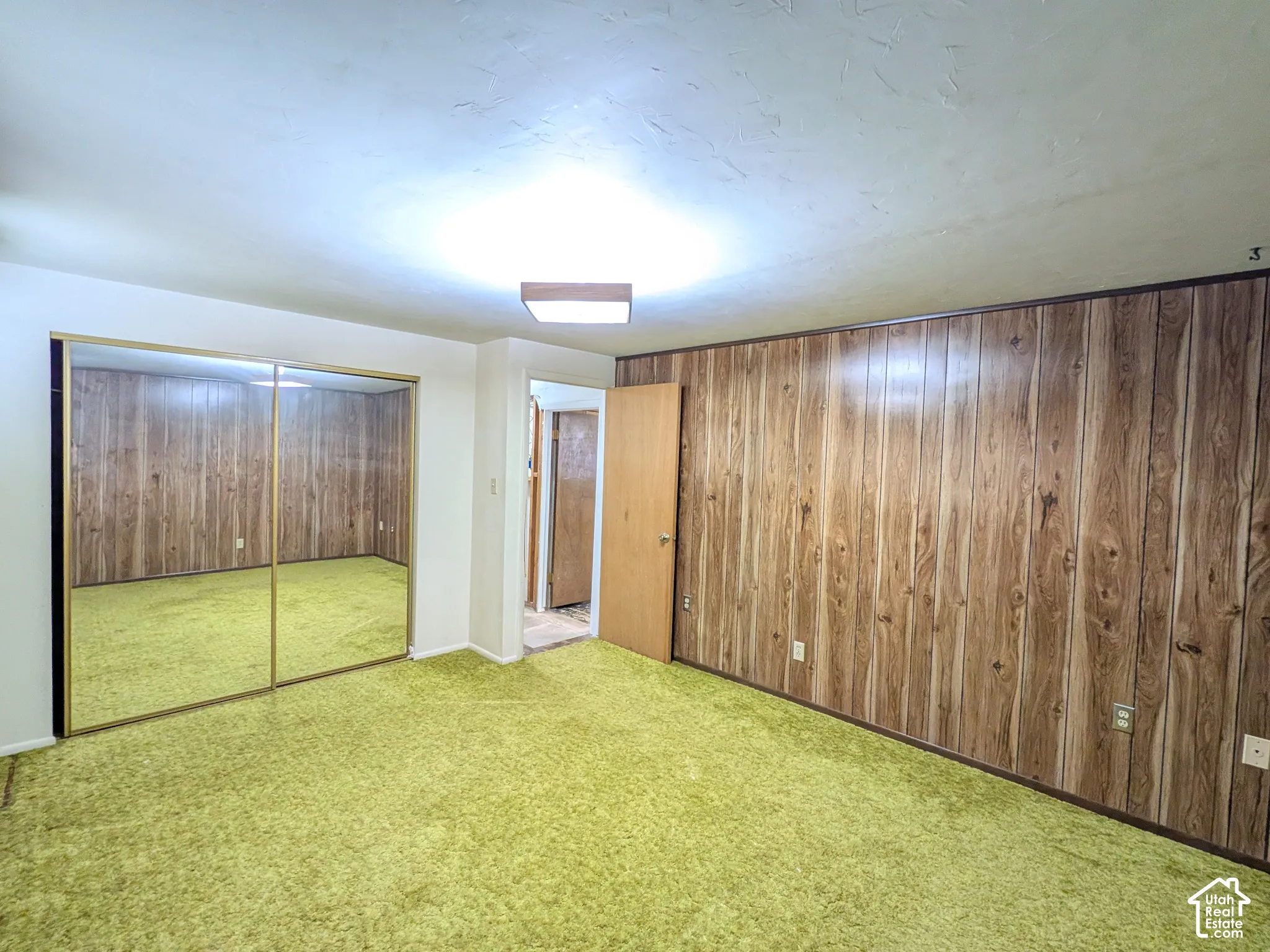 Wall paneling with wood-tone finish, mirrored closet doors, and recessed ceiling lighting